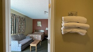 Una habitación de hotel con una cama, un sofá, una mesita y un toallero en la pared.