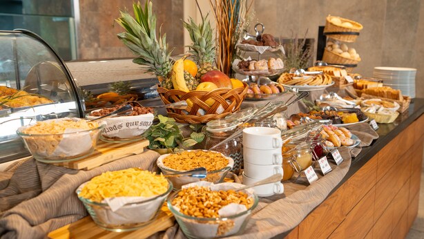 Ein Buffet mit verschiedenen Speisen, darunter Obst, Gebäck und Getreideprodukten.