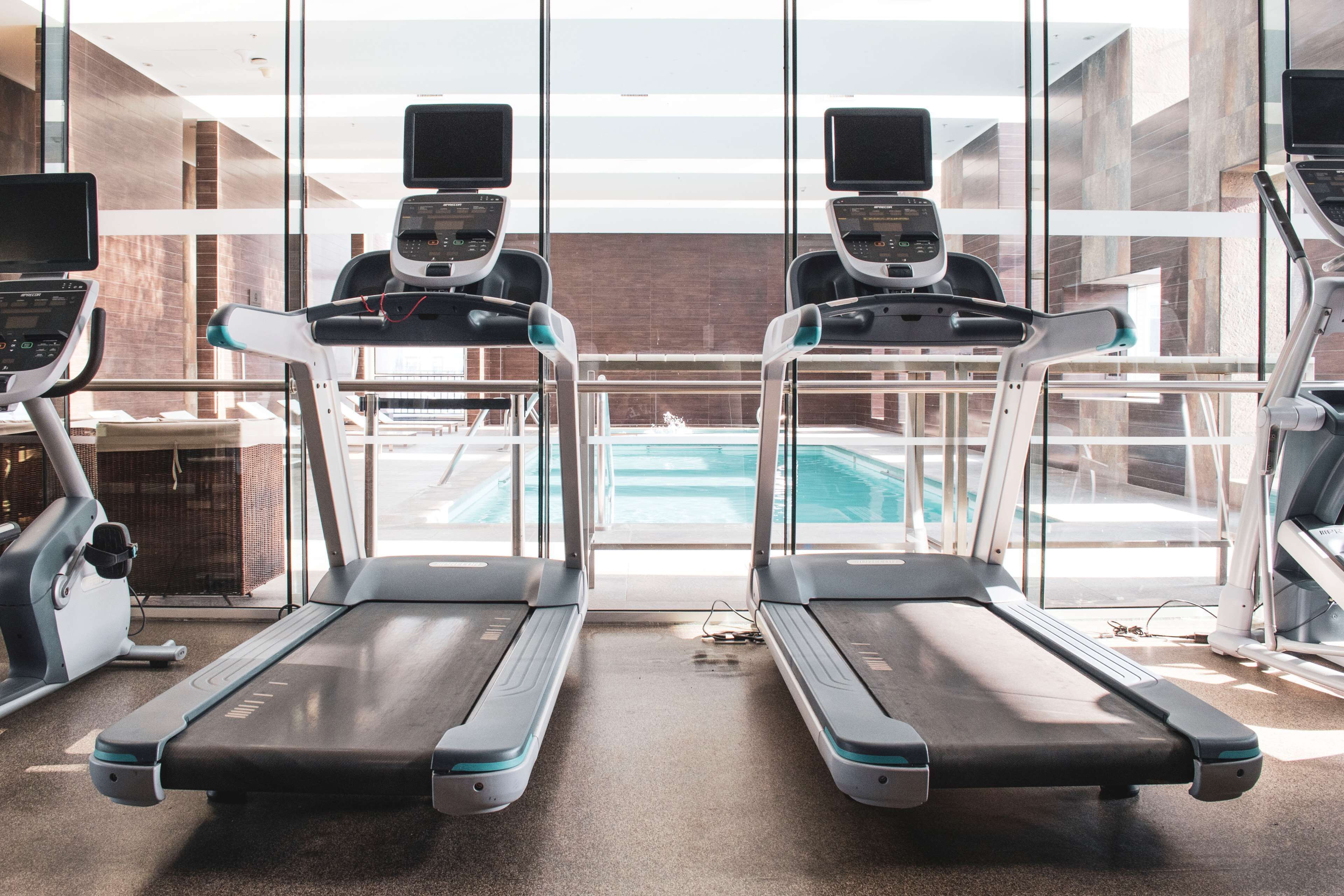 A gym with two treadmills, a pool, and large windows.
