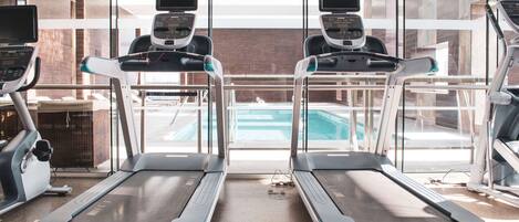 A gym with two treadmills, a pool, and large windows.
