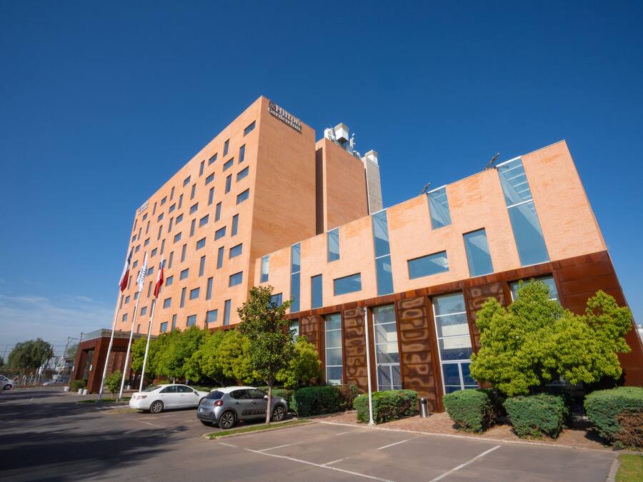 A modern hotel with a prominent tower, multiple parking spaces, and well-maintained landscaping.