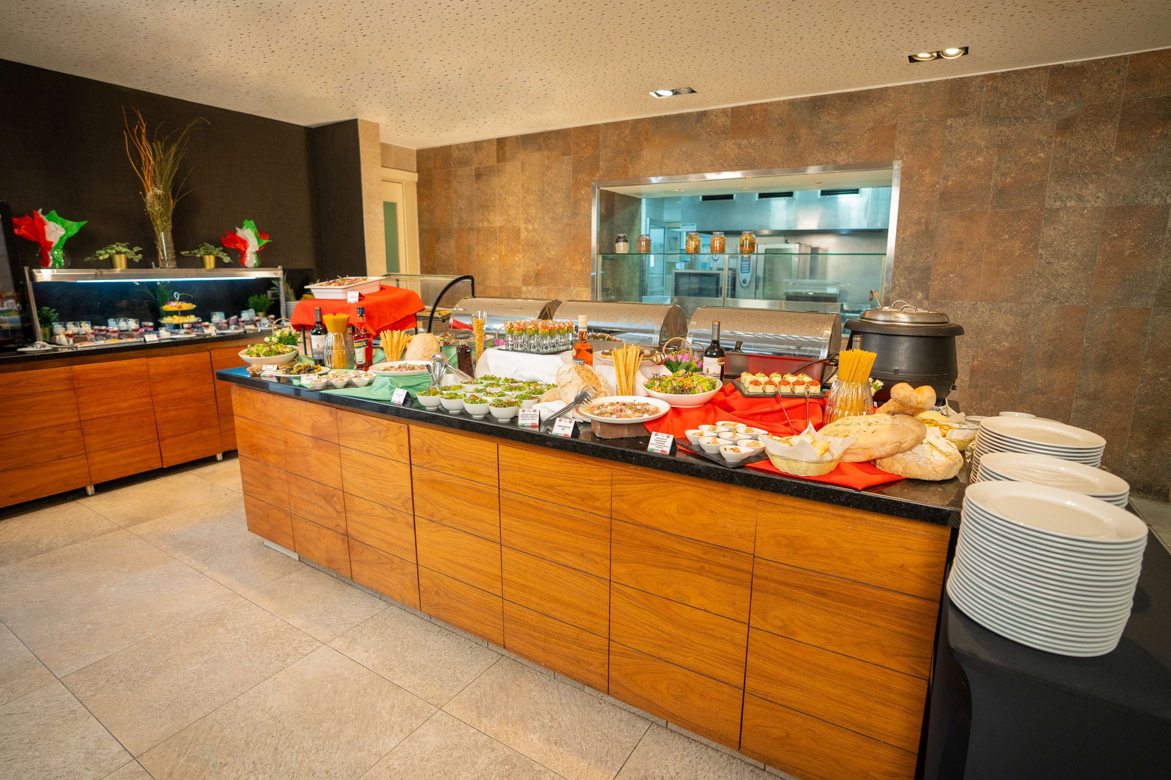 A buffet setup with various food items and a kitchen in the background.