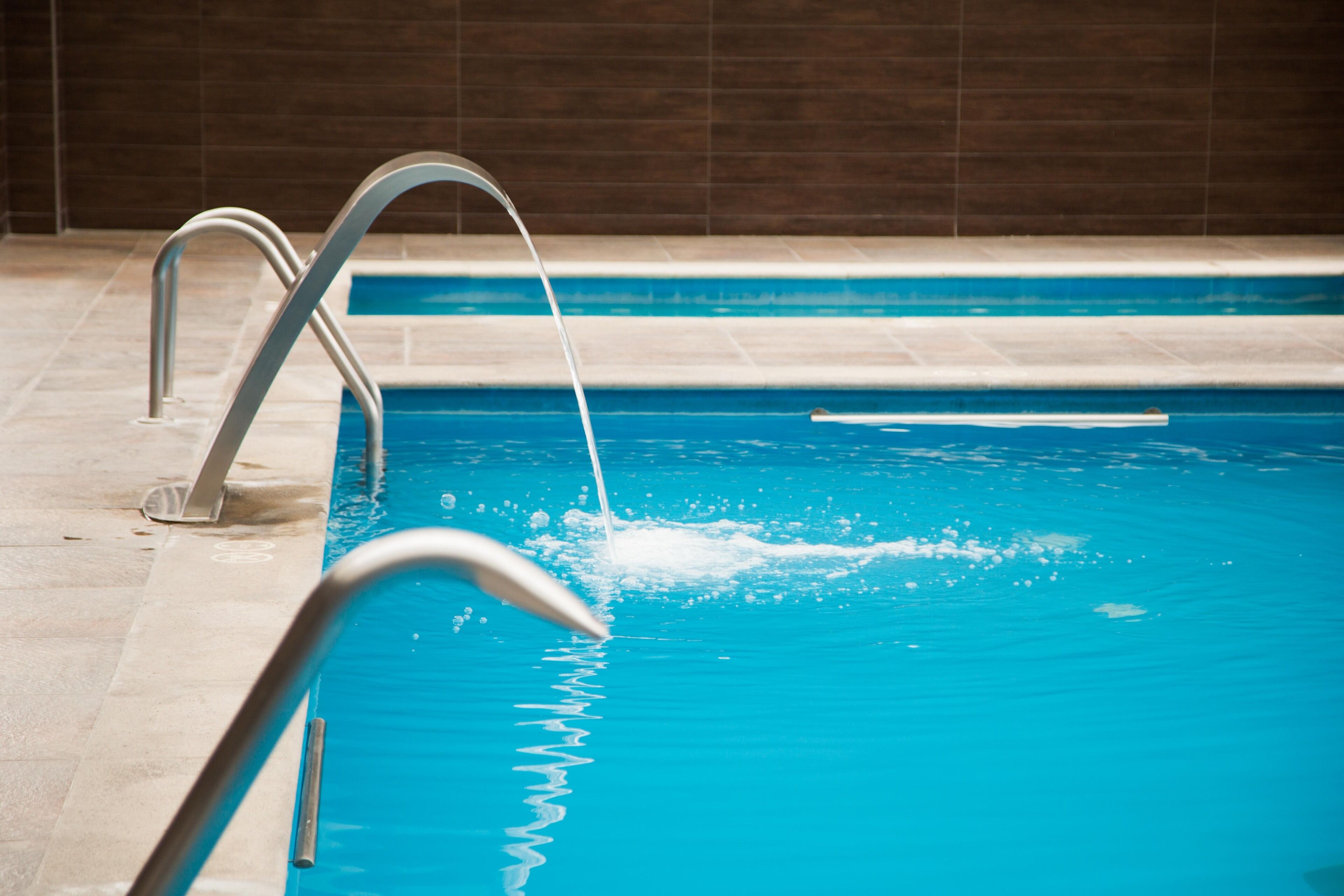 En swimmingpool med en metallstege och en vattenkran.