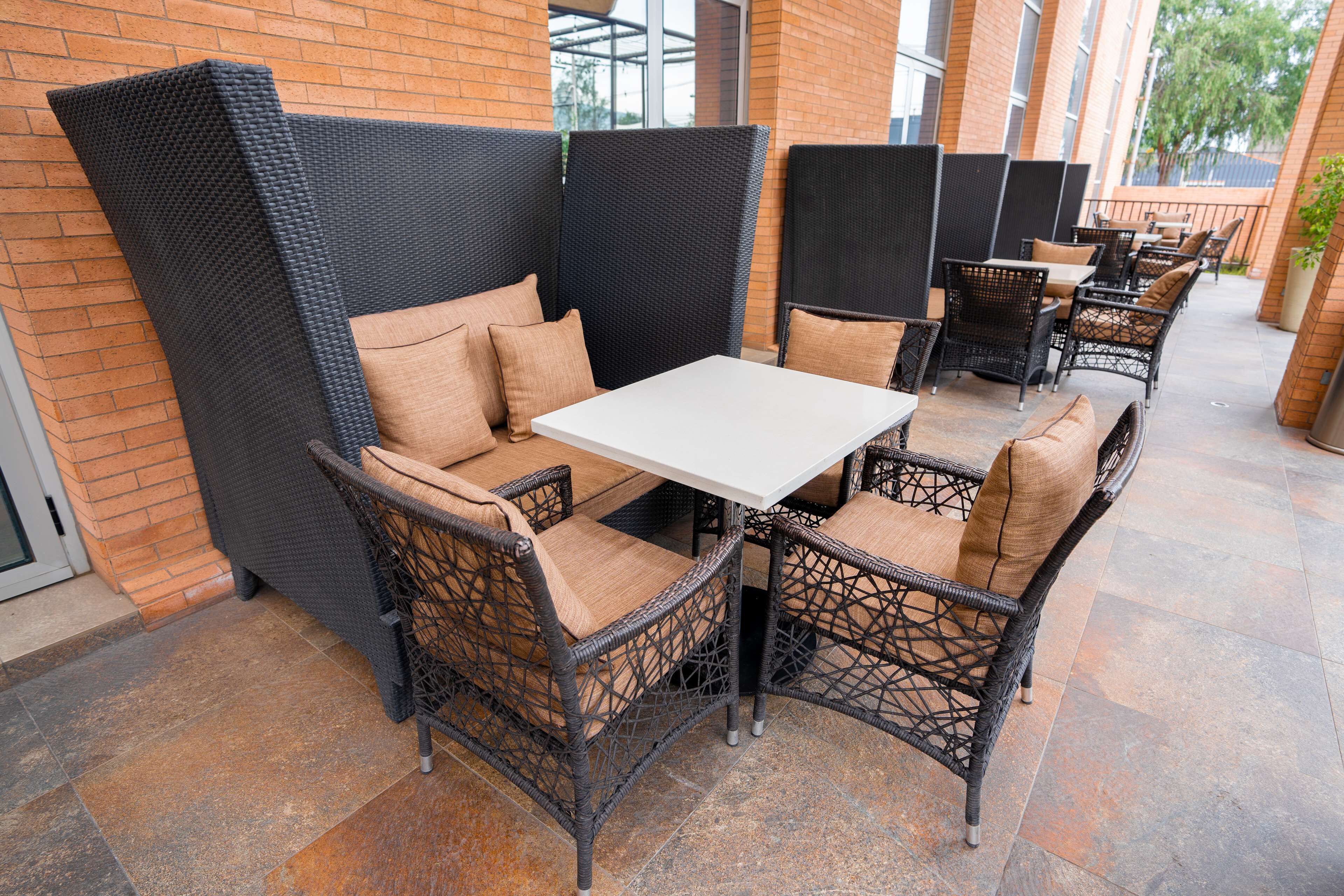 An outdoor patio with wicker furniture and a white table.