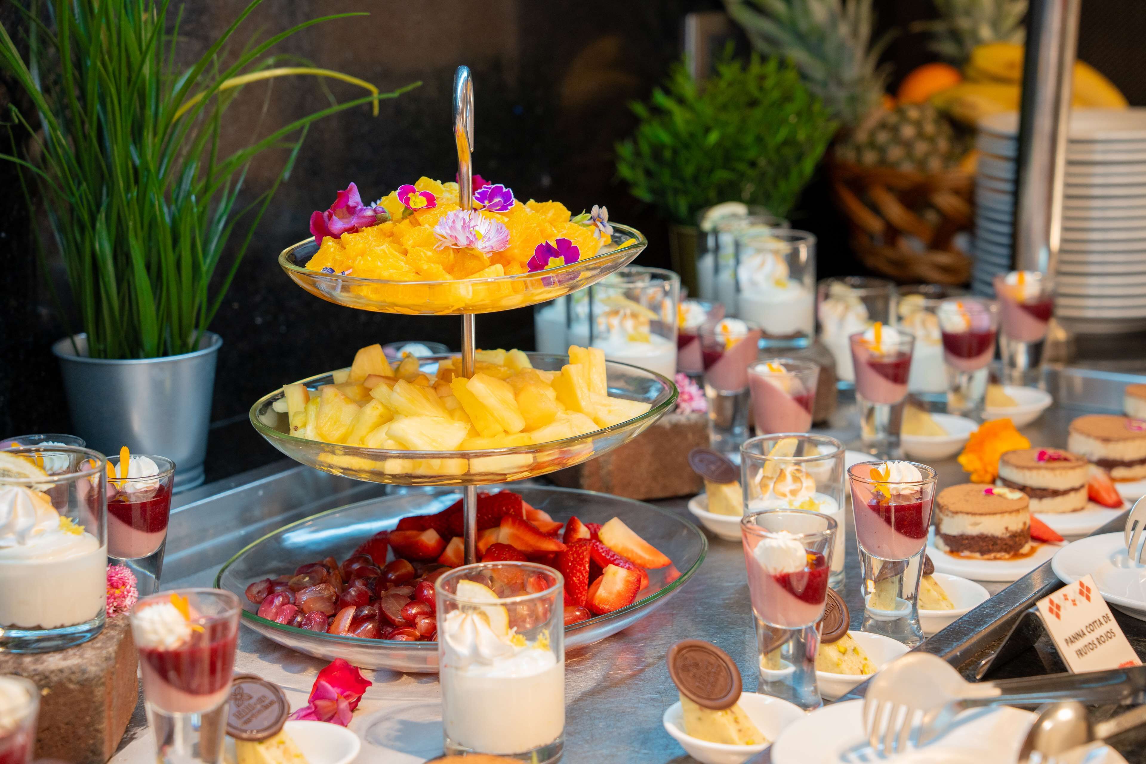 Un buffet con diverse pietanze tra cui frutta, dolci e bevande.