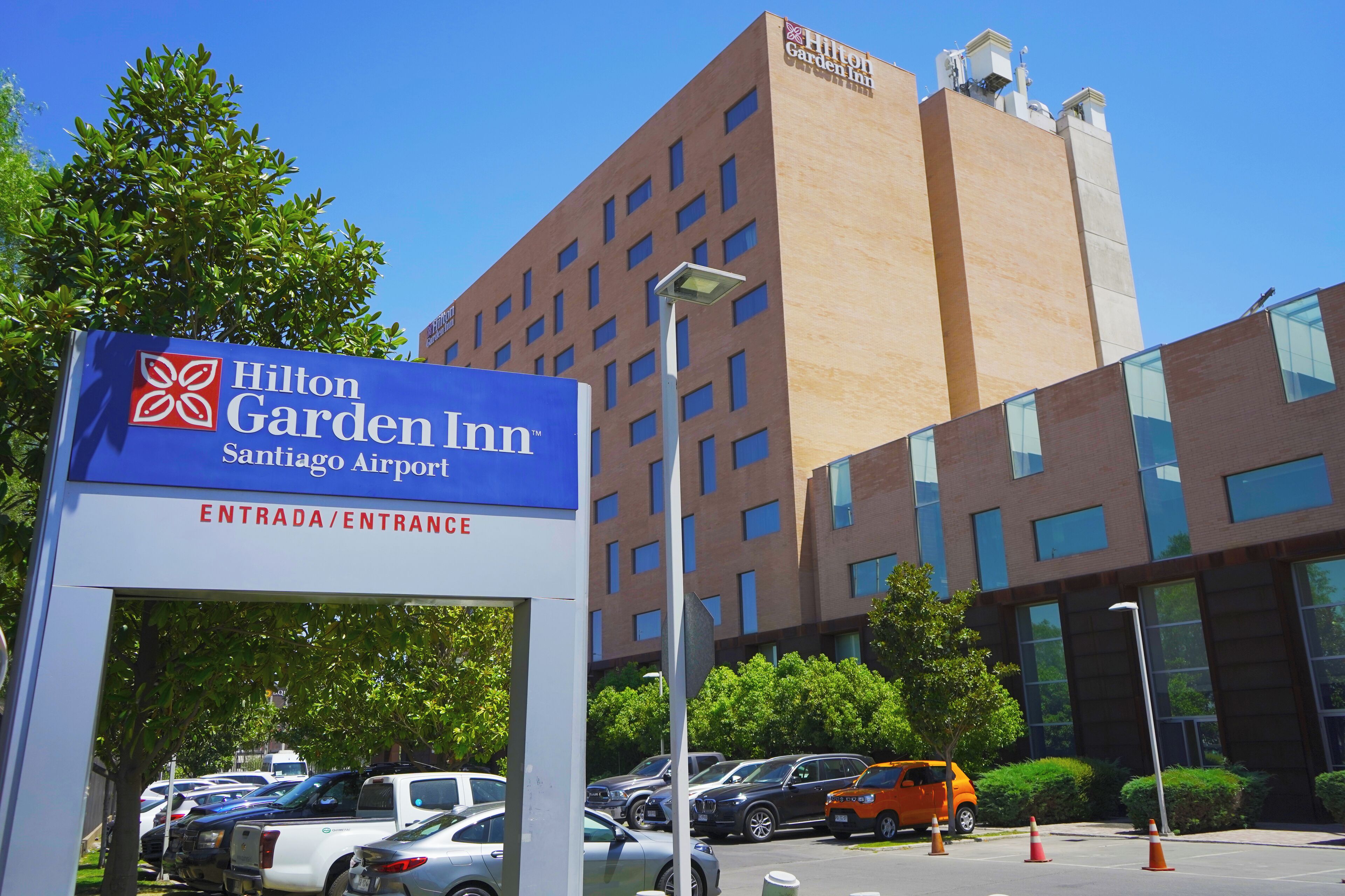 Ein Schild des Hilton Garden Inn am Eingang mit Blick auf das Gebäude und parkende Autos.