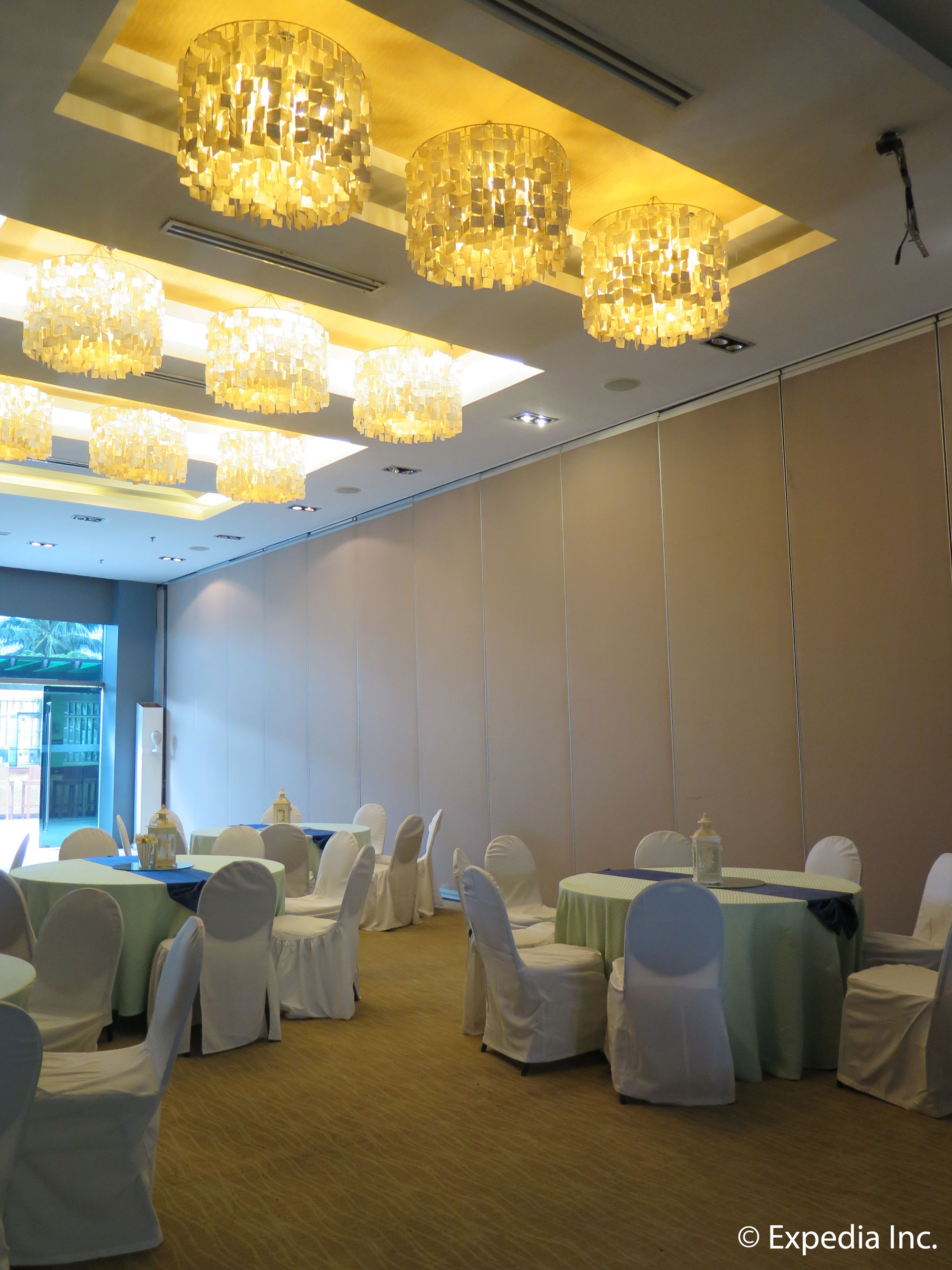 Un salón de conferencias con mesas redondas, sillas blancas y varios candelabros.