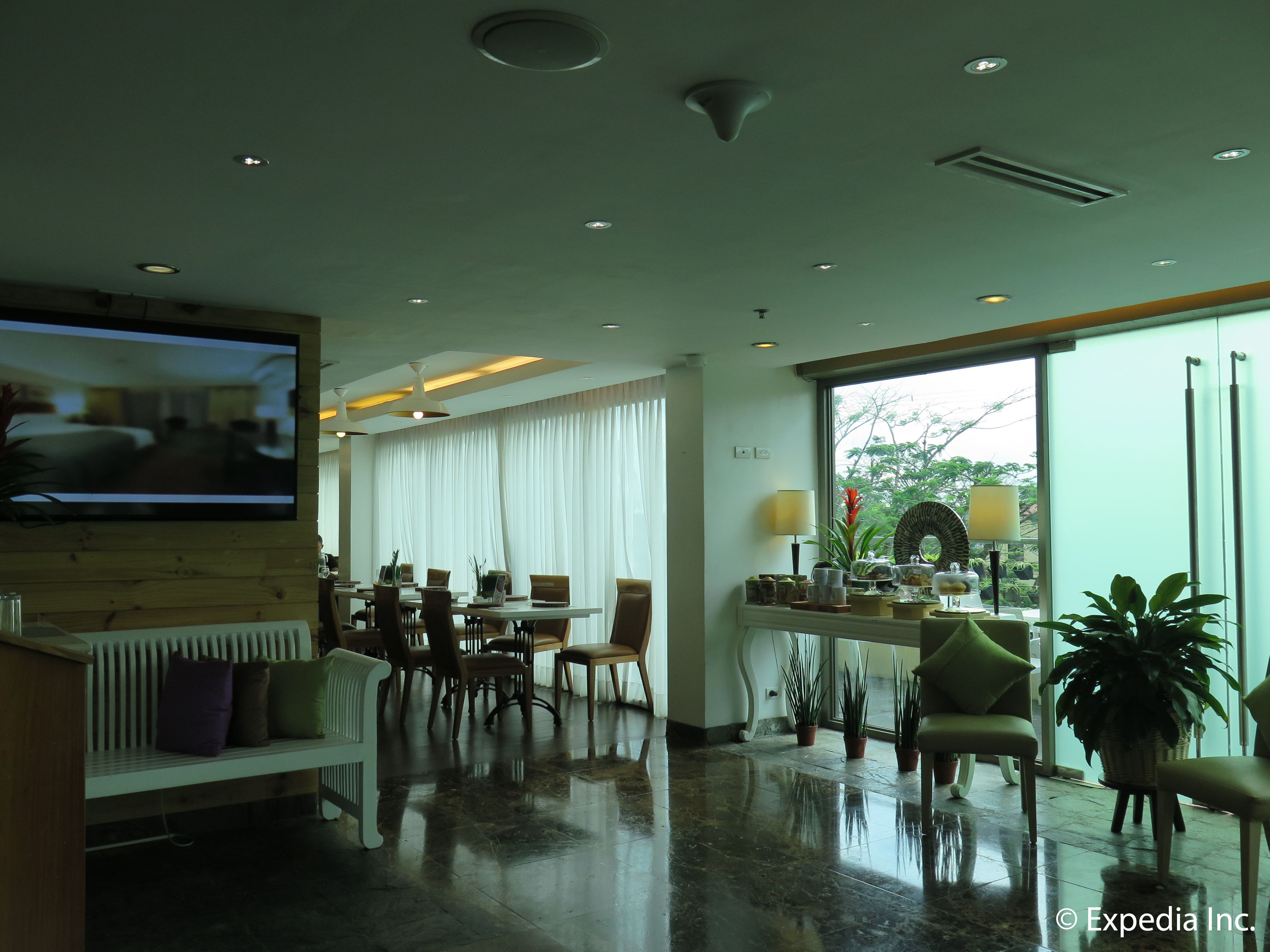 A hotel lobby with a TV, seating area, and large windows.