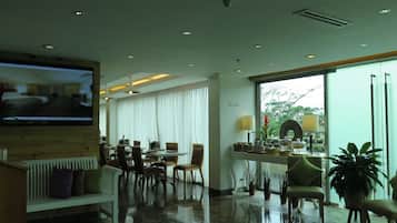 A hotel lobby with a TV, seating area, and large windows.
