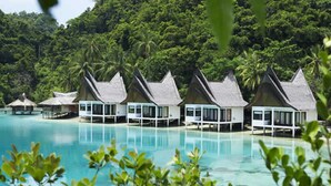 Overwater bungalows with a pool, surrounded by lush greenery.