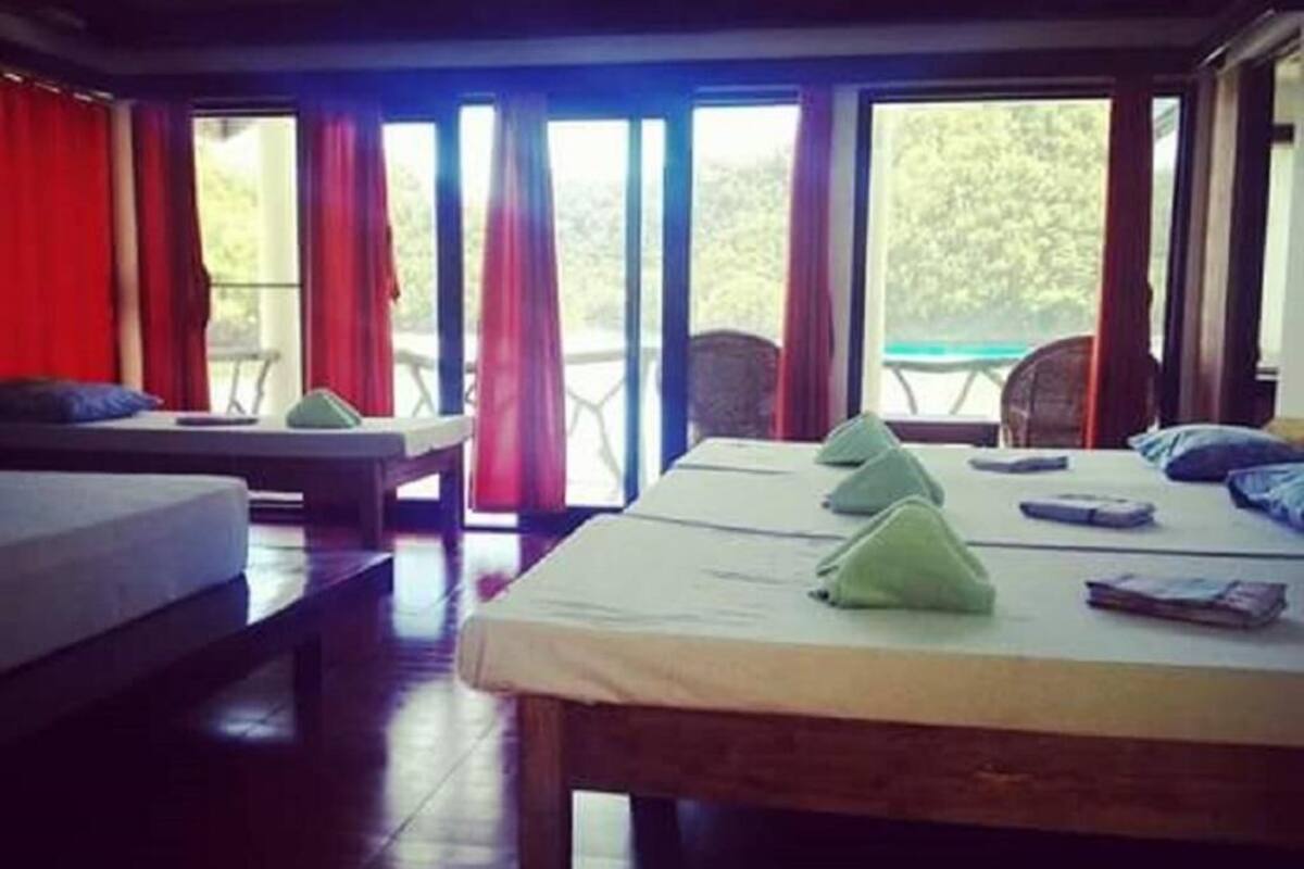 Ein Zimmer mit zwei Betten, einer Bank und einem Tisch mit Stühlen.