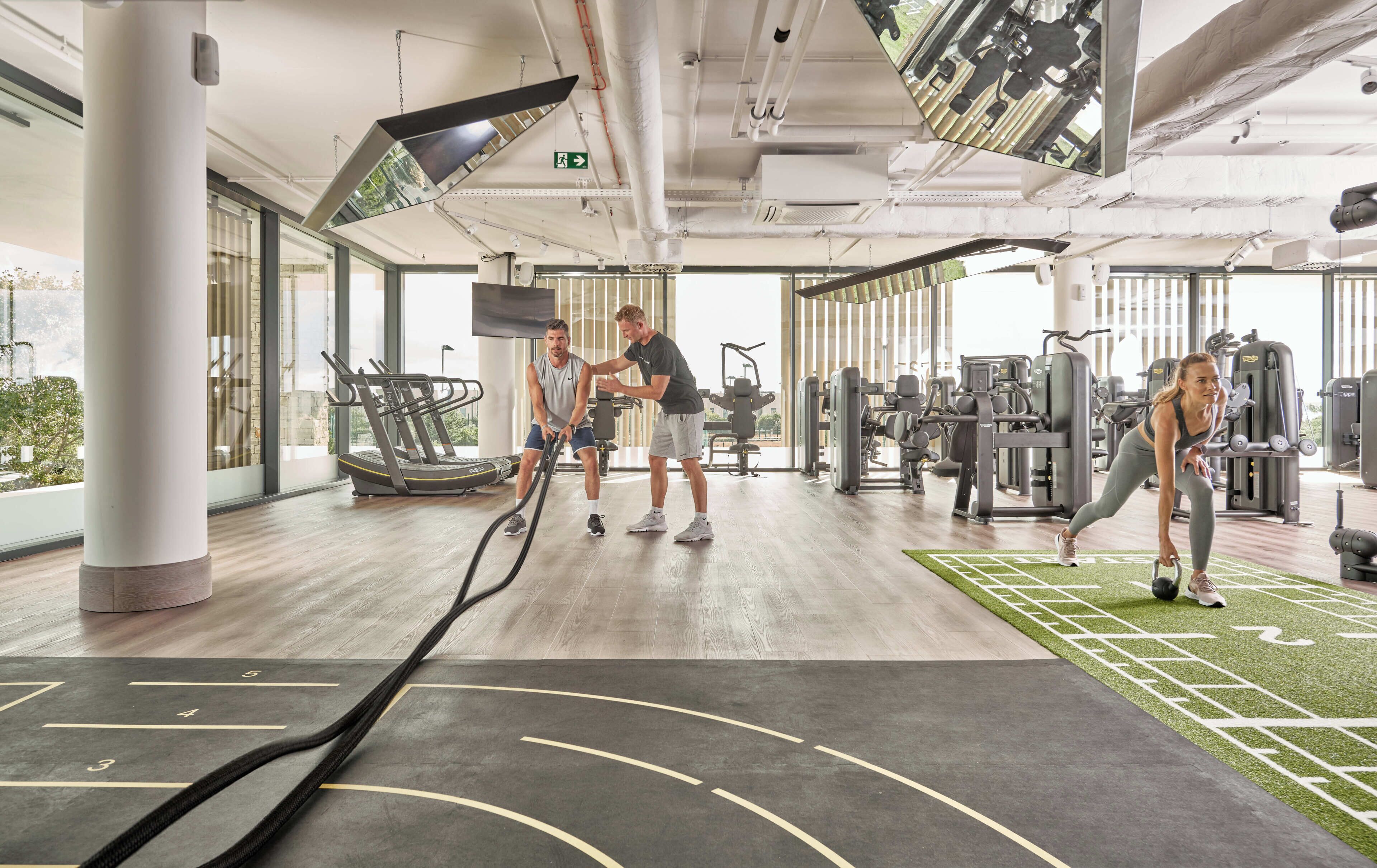 A gym with treadmills, weight machines, and a large mirror.