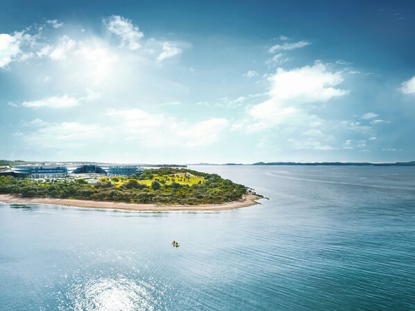 An aerial view of a coastal property with a beach, a small island with greenery, and a body of water. - Falkensteiner Hotel & Spa Iadera (Zadar)