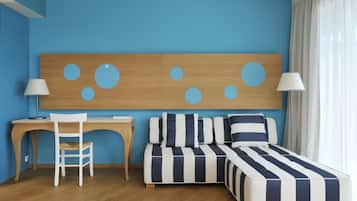A room with a desk, a chair, a bed with striped bedding, a sofa, and a large wall decoration.