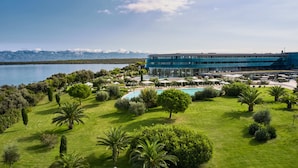 A modern hotel with a pool, surrounded by lush greenery and a view of a lake and mountains. - Falkensteiner Hotel & Spa Iadera (Zadar)