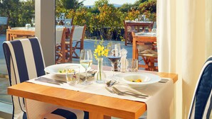 A dining table set with plates, glasses, and cutlery, overlooking a garden with tables and chairs. - Falkensteiner Hotel & Spa Iadera (Zadar)