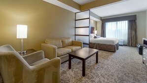 A hotel room with a sofa, armchair, coffee table, and a bed with a view of the city. - Best Western Plus Lacey Inn & Suites (Olympia)
