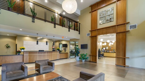 A spacious lobby with a reception desk, seating area, and a second-floor balcony with plants. - Best Western Plus Lacey Inn & Suites (Olympia)