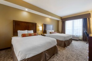 A hotel room with two beds, a large window with curtains, a flat-screen TV, and an air conditioning unit. - Best Western Plus Lacey Inn & Suites (Olympia)