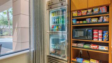 A vending machine with a variety of snacks and drinks, and a microwave above it.