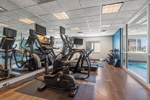 A gym with cardio machines, mirrors, and a view of a swimming pool. - Holiday Inn Express Tulsa South Bixby by IHG (Tulsa)