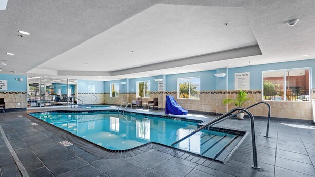 Piscina interior com água cristalina, chão azulejado e um escorregador azul.