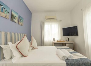 Ein Hotelzimmer mit Bett, Schreibtisch, Fernseher und Kunstwerk an der Wand.