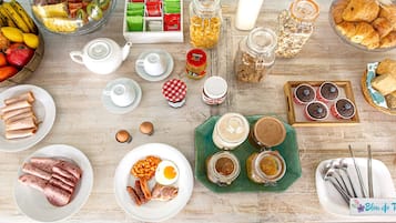 A breakfast spread with various foods and drinks on a wooden table.