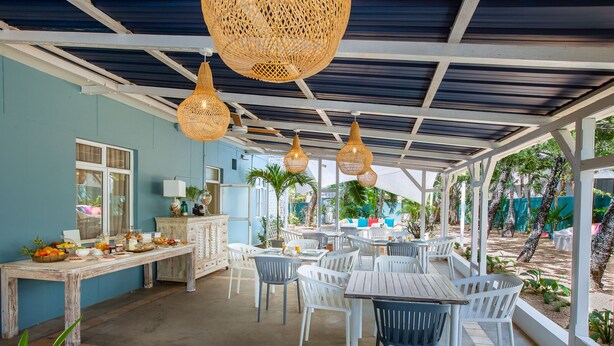 An outdoor dining area with white tables and chairs, a buffet table with food, and hanging wicker lamps. - Bleu de Toi - Boutique Guest House (Grand-Baie)