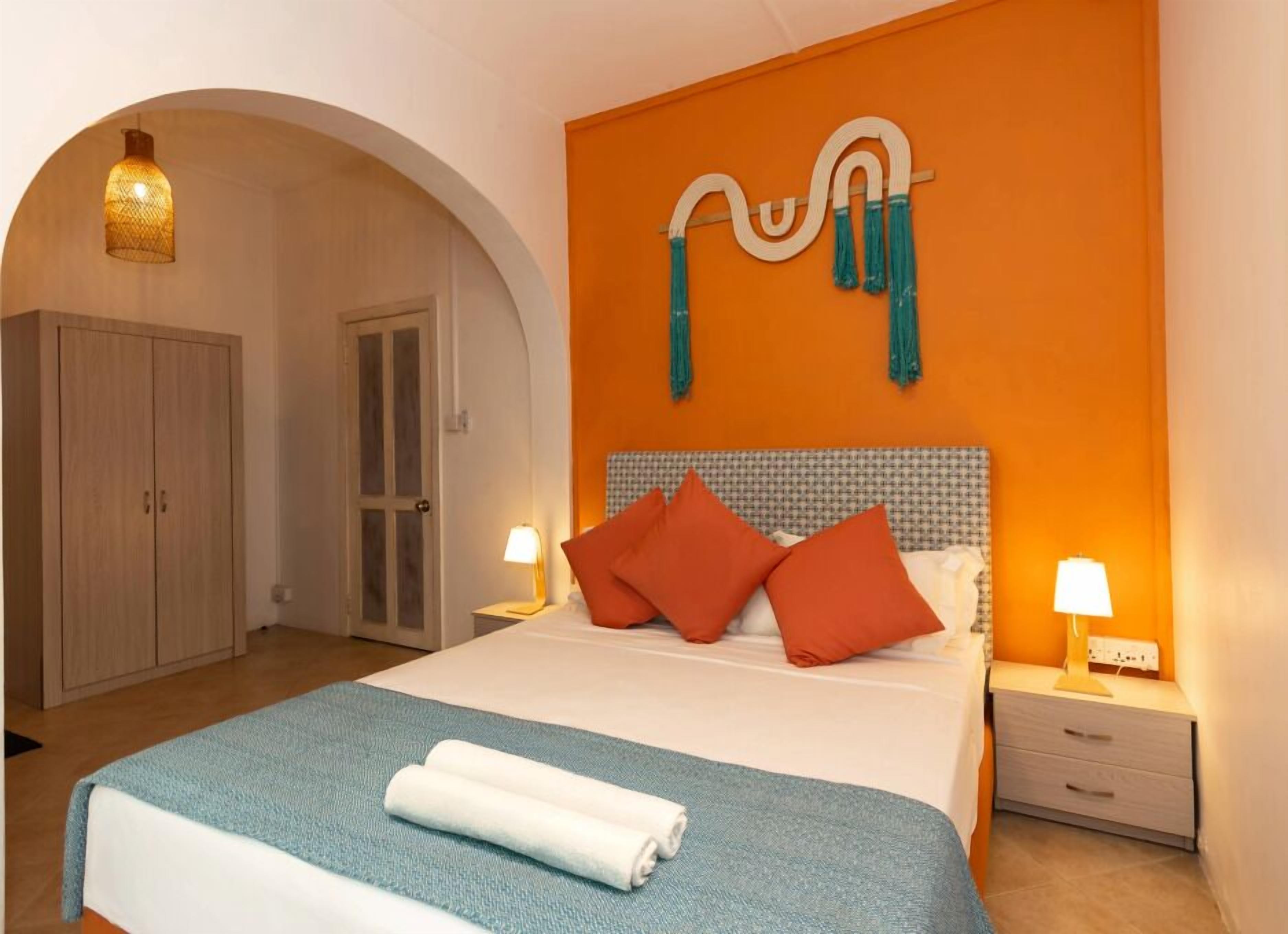 Una habitación de hotel con cama, armario, mesita de noche y una obra de arte en la pared.