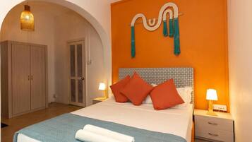 Una habitación de hotel con cama, armario, mesita de noche y una obra de arte en la pared.