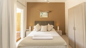 A bedroom with a bed, bedside tables, a ceiling fan, a nightstand, a wardrobe, and a painting on the wall. - Bleu de Toi - Boutique Guest House (Grand-Baie)