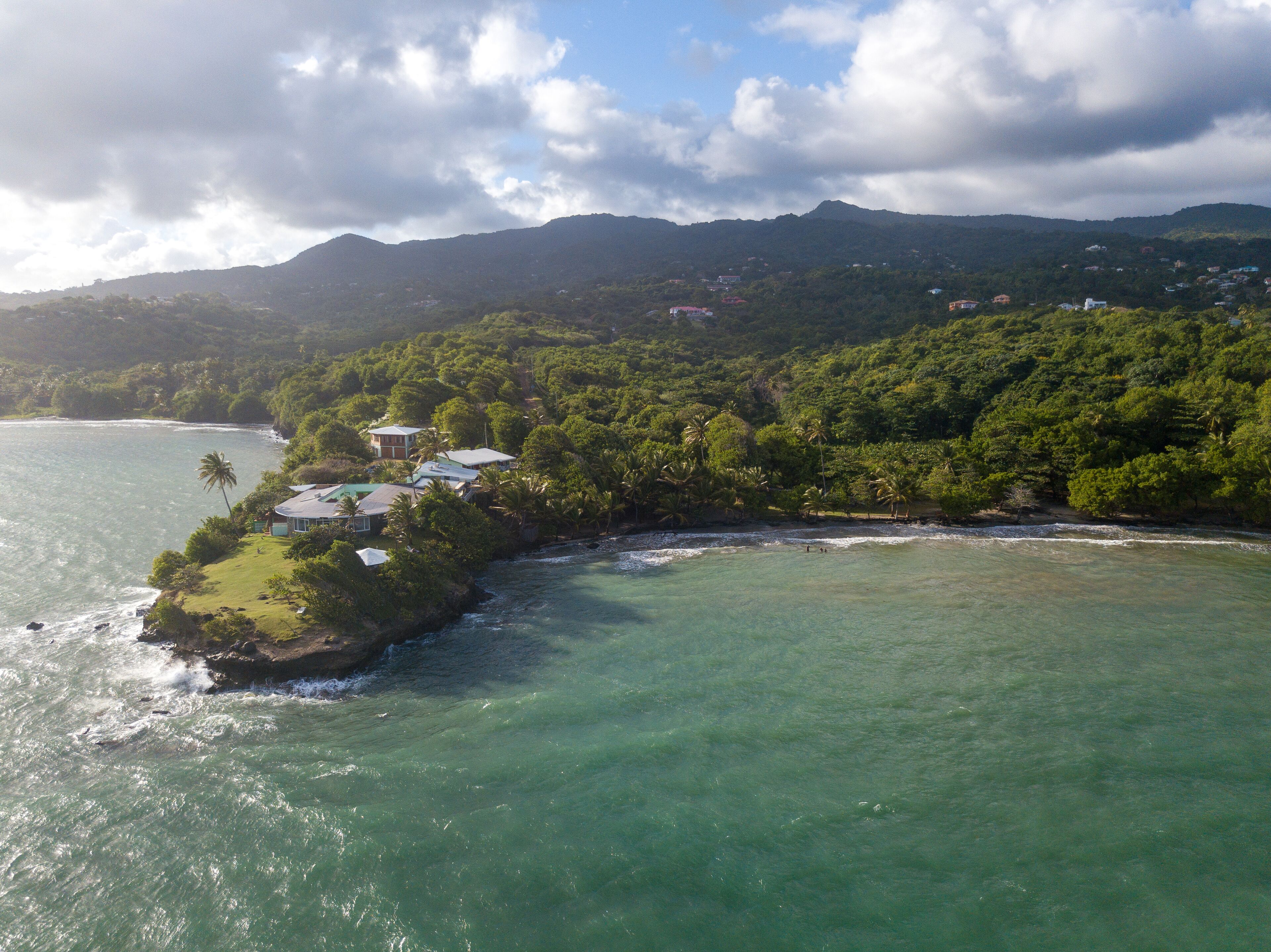 A coastal property with a view of the ocean and a mountainous backdrop.
