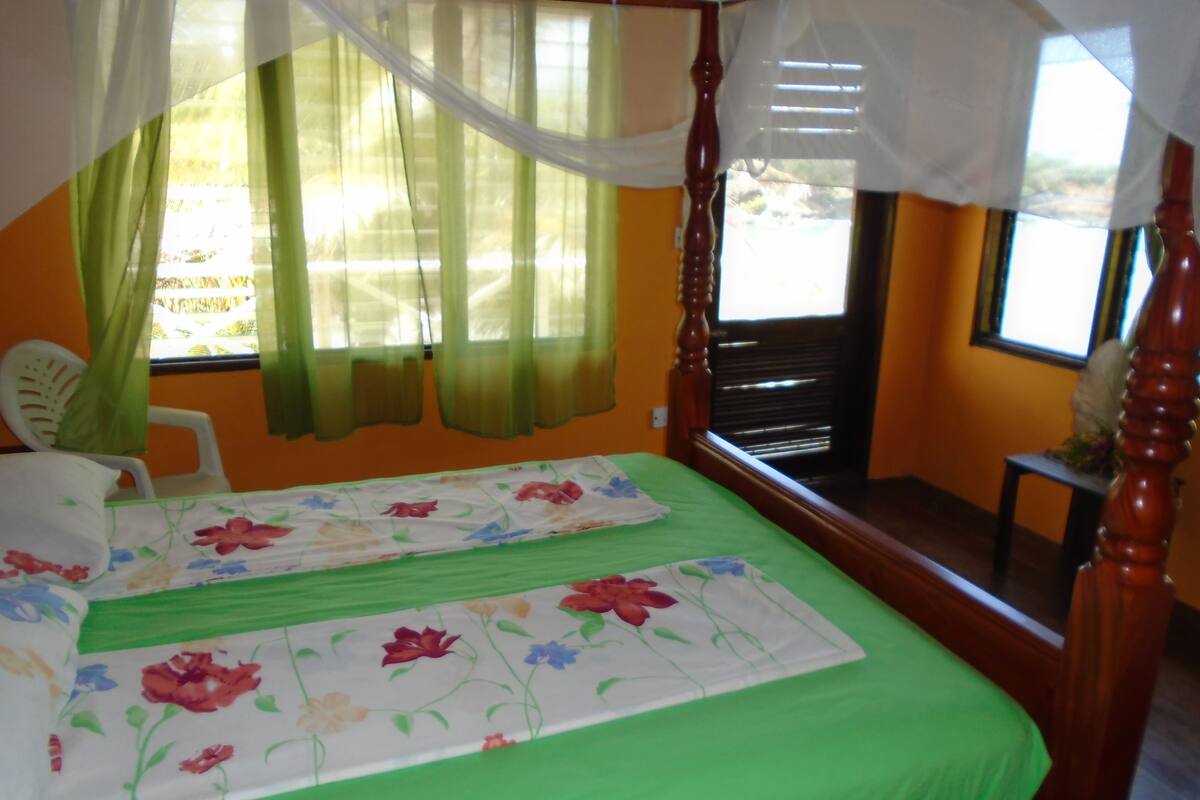 Quarto com cama, cadeira e janela com cortinas.