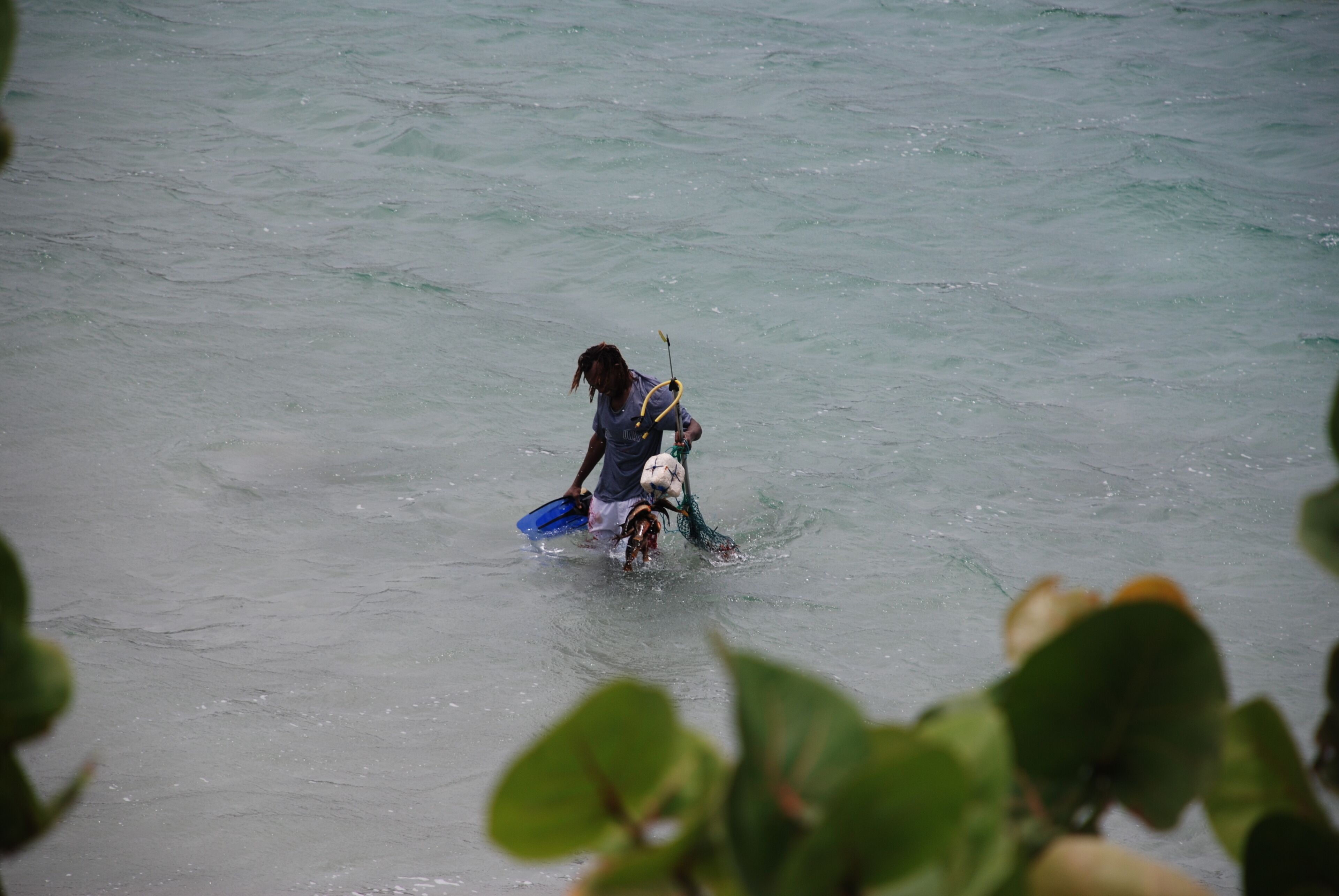 Una persona en el agua con una caña de pescar y un objeto azul.