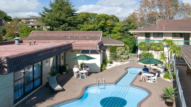 Une piscine dont le design est inspiré d’une guitare, entourée d’un espace de détente extérieur et d’une terrasse en briques.