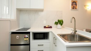 Une cuisine moderne équipée d’un four à micro-ondes encastré, d’un évier en acier inoxydable et d’une plante en pot.