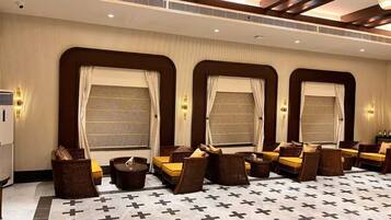 Habitación de hotel con un amplio espacio de estar, varias ventanas con cortinas y un suelo estampado.