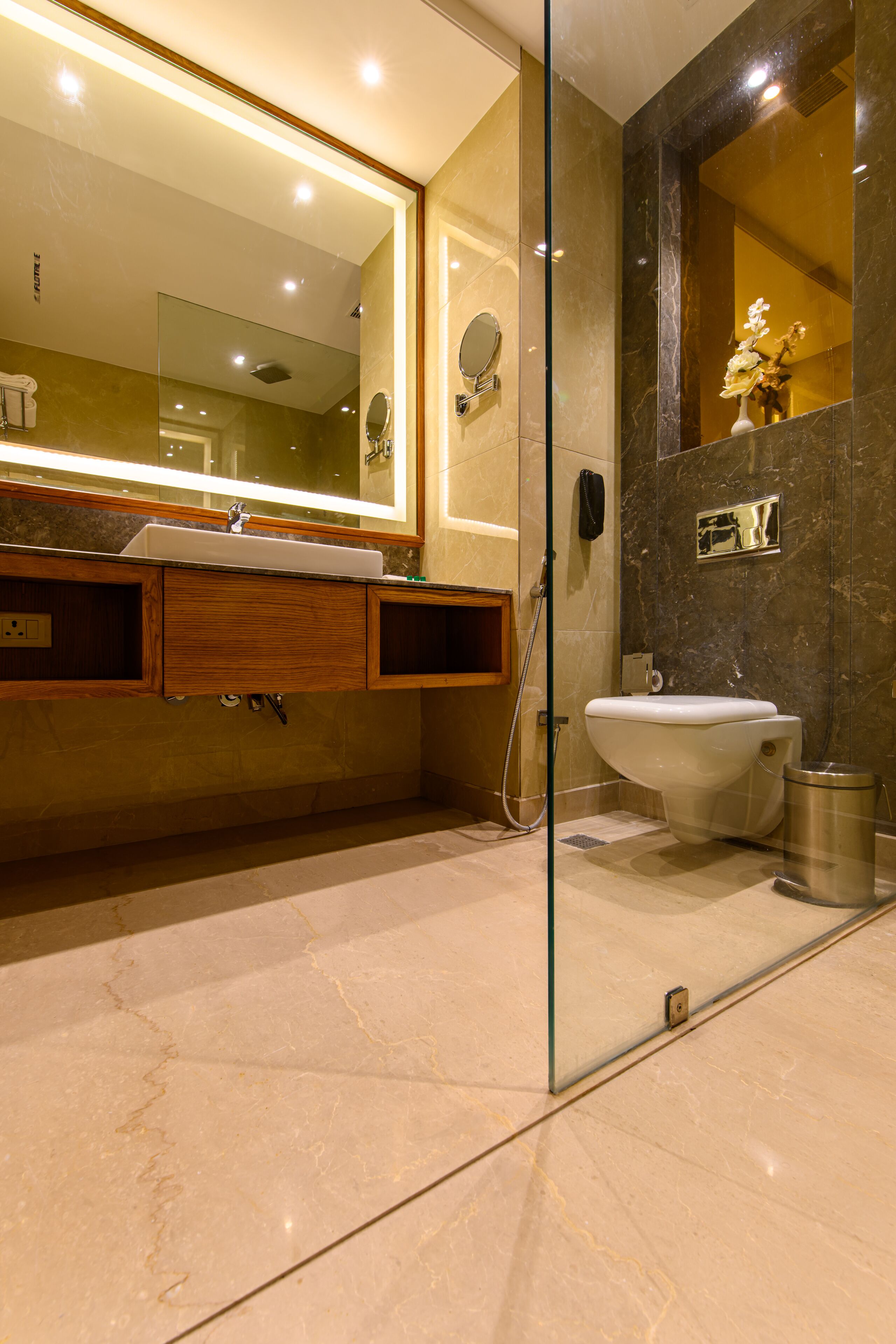 Une salle de bain moderne dotée d’une douche à parois de verre, d’un lavabo avec un meuble-vasque en bois et d’un grand miroir placé au-dessus du lavabo.