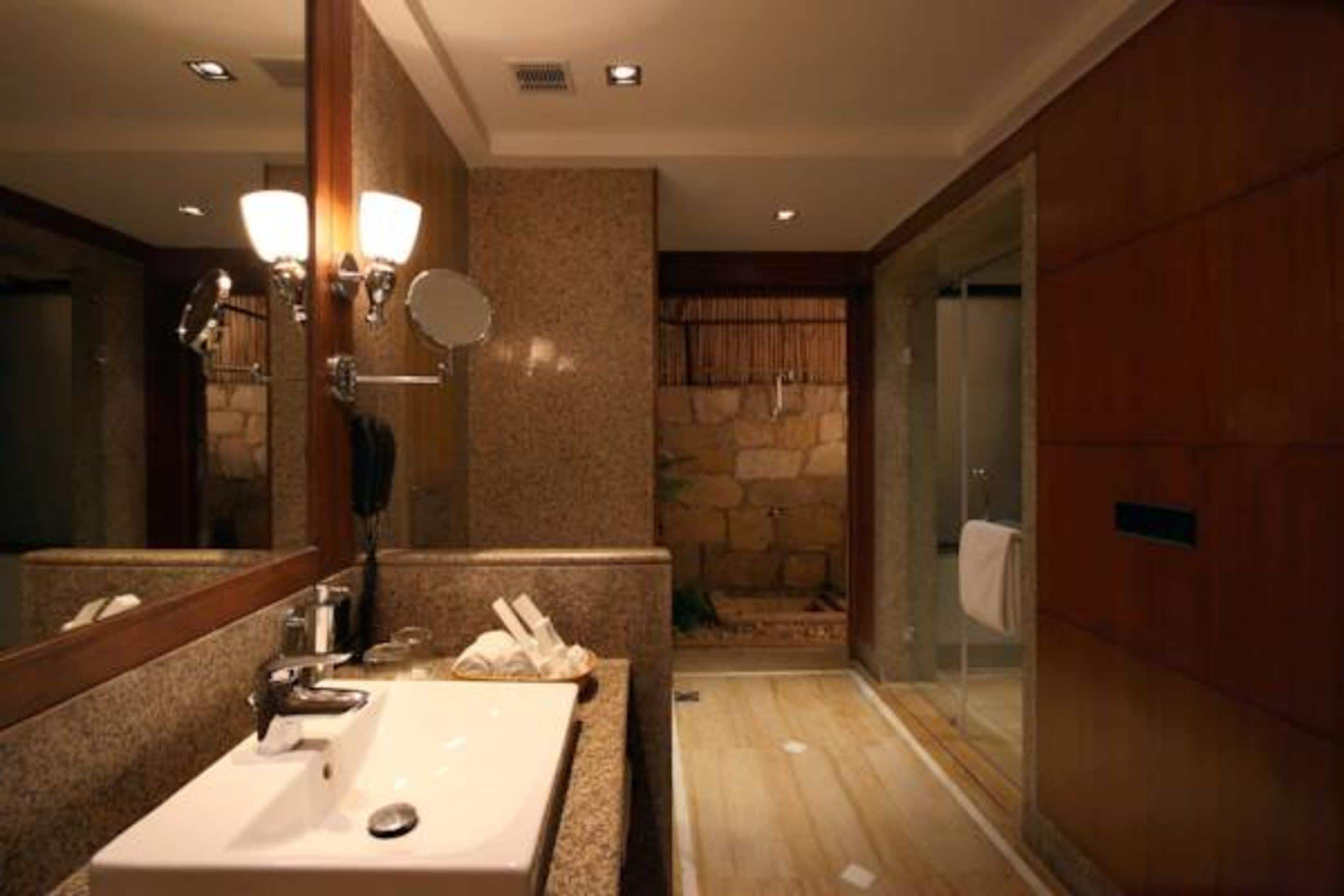 A bathroom with a large mirror, a sink, and a shower area.