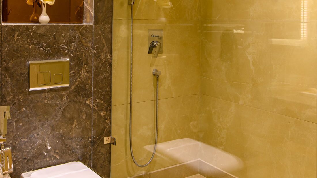 A bathroom with a marble wall, a shower, and a toilet.