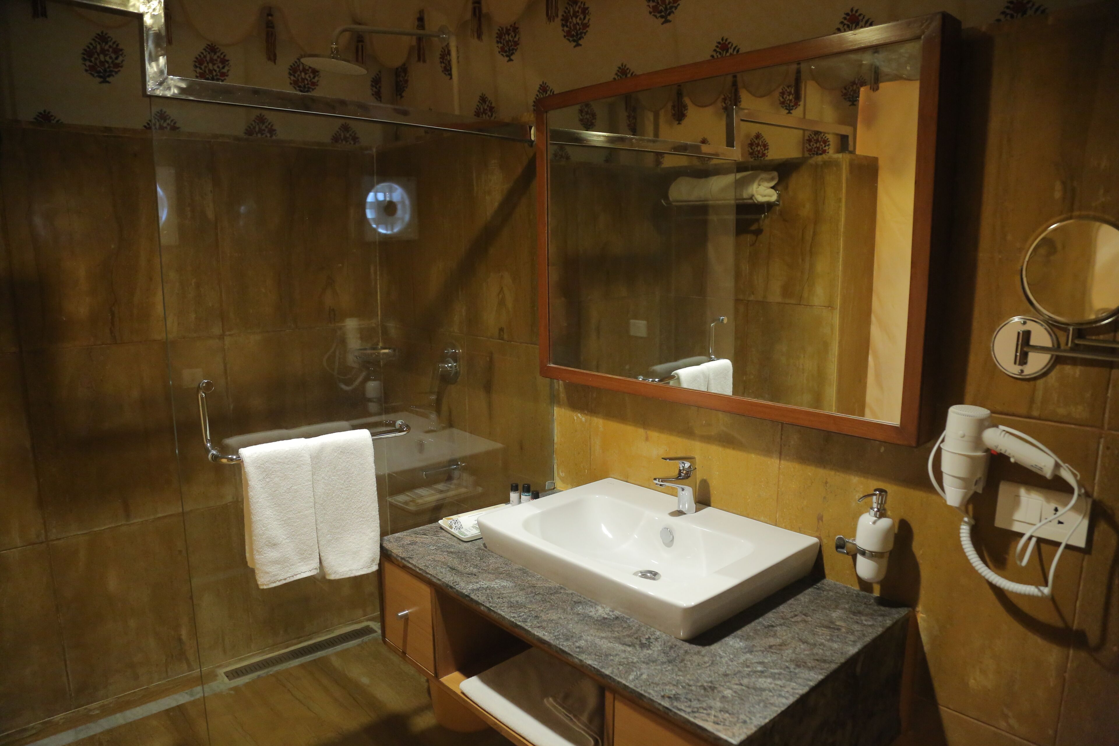 A bathroom with a sink, mirror, towel rack, and a shower.
