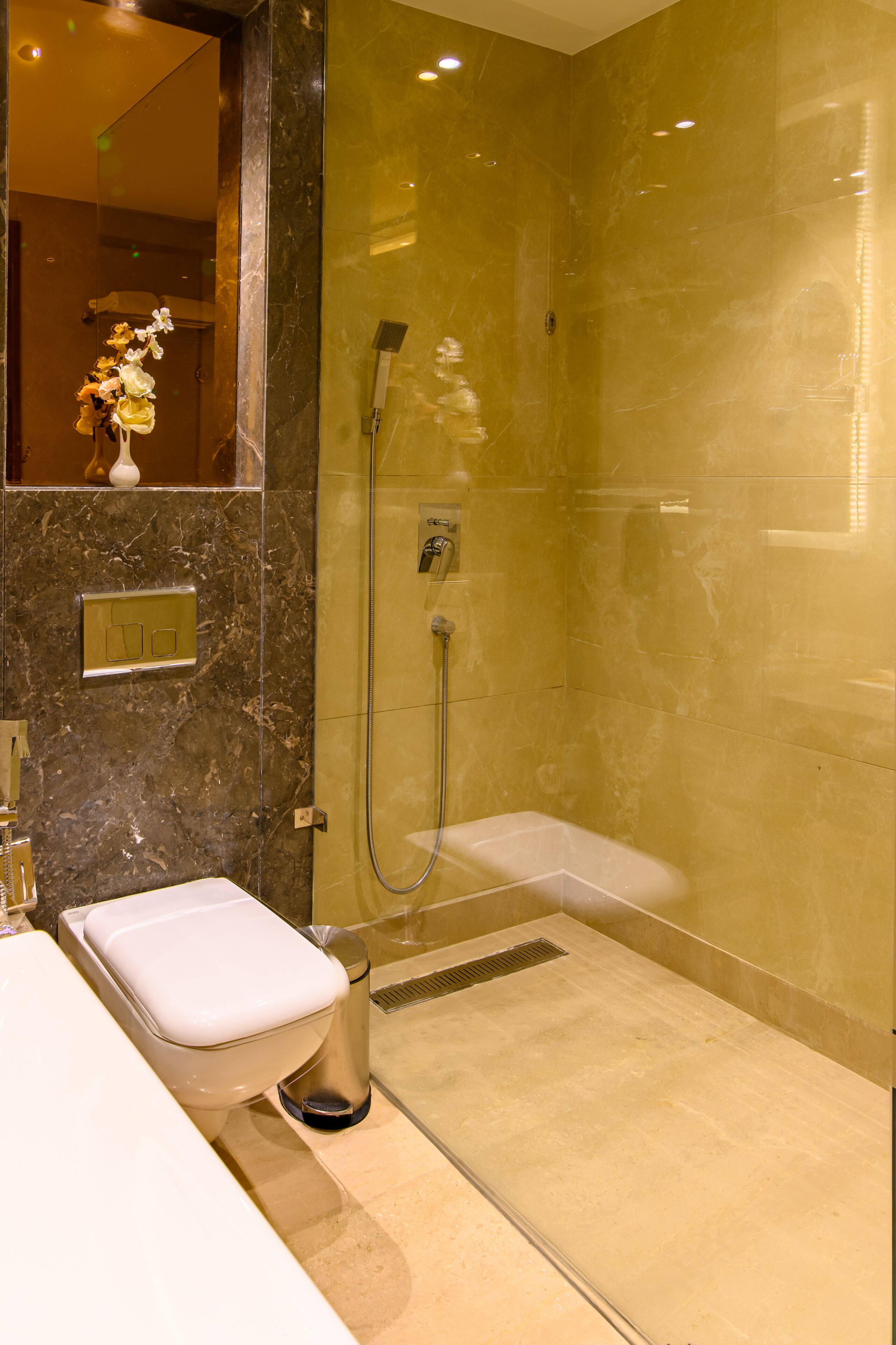 A modern bathroom with a glass-enclosed shower, a white sink, and a marble wall.