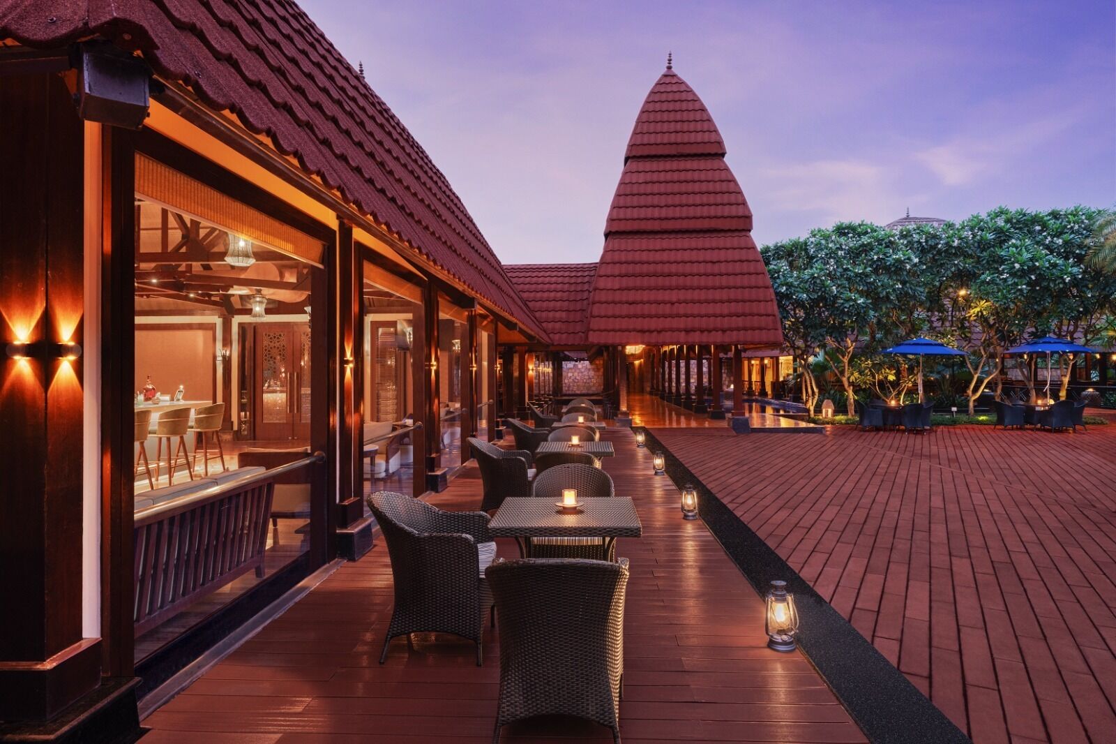 A restaurant with outdoor seating, a distinctive red-roofed structure in the background, and a wooden deck.