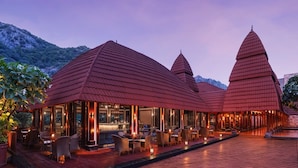 A restaurant with a red roof and multiple dining areas, set against a mountainous backdrop. - Ananta Spa and Resorts (Pushkar)