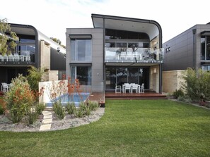 A modern two-story house with a flat roof, large windows, and a well-maintained lawn. - Aqua Resort Busselton (Broadwater)