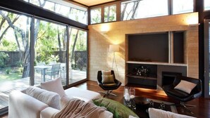 A modern living room with a fireplace, large windows, and a view of the outdoors. - Aqua Resort Busselton (Broadwater)