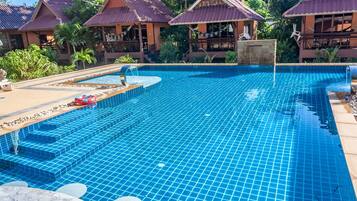 Een buitenzwembad, ligstoelen bij het zwembad