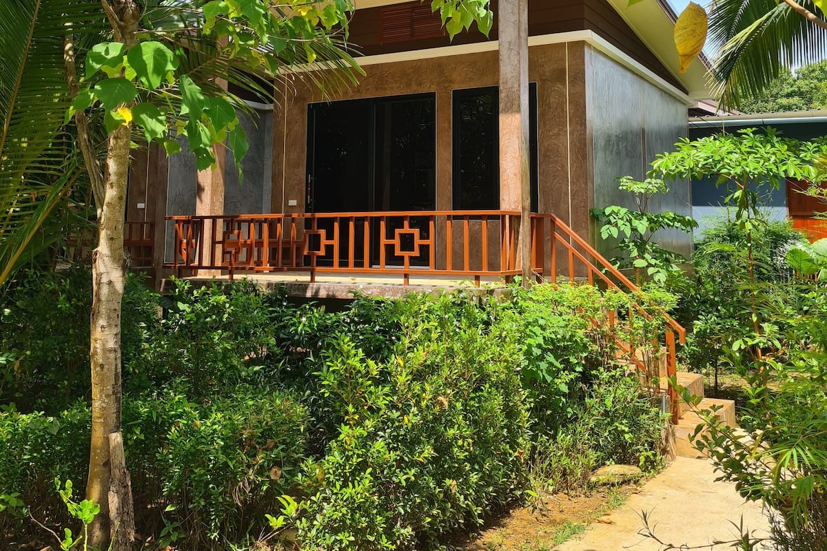 Un immeuble doté d’un balcon, entouré de verdure.