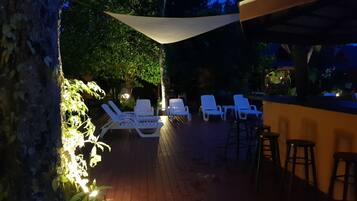 A patio area with white lounge chairs and a bar area.
